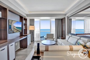 A modern hotel room with a large TV, a sofa, a coffee table, and a view of the ocean. - 1BR condo w/ hot tub & gym access (Fort Lauderdale)