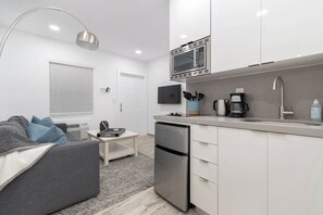 A compact kitchen with a microwave, coffee maker, and dishwasher. - Modern apt w/queen bed & beach steps (Hollywood)