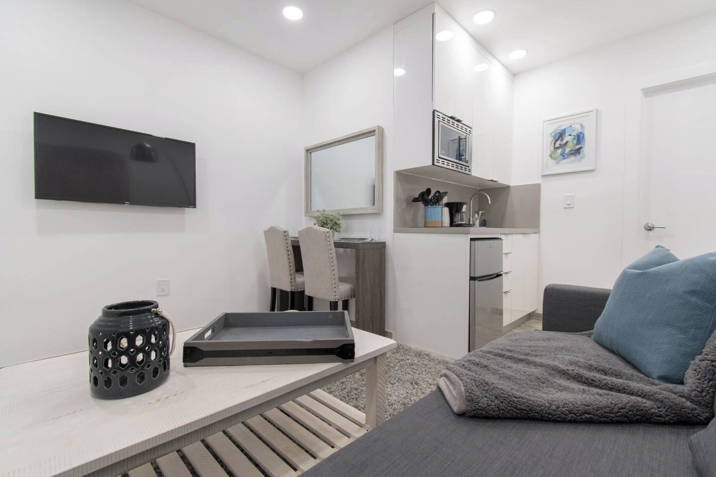 A modern, compact living space with a kitchenette, a flat-screen TV, a dining area, and a cozy seating area.