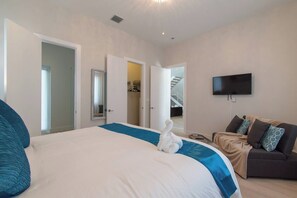 A bedroom with a large bed, a sofa, a television, and a staircase leading to another room. - Modern villa close to beach w/ heated pool & grill (Hollywood)