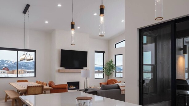Una cocina moderna con una isla grande, un comedor con mesa de madera y una sala de estar con sofá y chimenea.