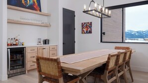 Una cocina moderna con una mesa y sillas de madera, un refrigerador para vino empotrado y obras de arte en las paredes.