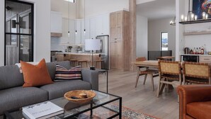 Una sala moderna con un sofá gris, una mesa de centro y un comedor con sillas y una mesa de madera.