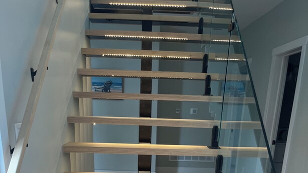 Una escalera moderna con escalones de madera y barandillas de vidrio.