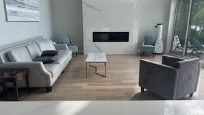 Una sala de estar moderna con chimenea de mármol, sofás de cuero y piso de madera.