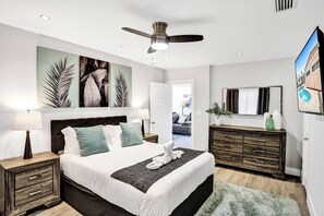 A bedroom with a bed, nightstands, a dresser, a ceiling fan, and artwork on the walls. - Spacious home w/pool, fire pit & grill (Lighthouse Point)