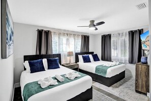 A hotel room with two beds, a ceiling fan, a TV, and a view of the outside. - Spacious home w/pool, fire pit & grill (Lighthouse Point)