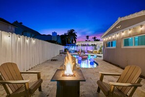 A backyard with a fire pit, outdoor seating, a swimming pool, and a covered patio area. - Spacious home w/pool, fire pit & grill (Lighthouse Point)