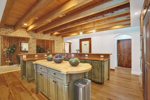 A spacious kitchen with a large island, wooden beams, and a stone wall. - Family villa w/ heated pool, gameroom & fire pit (Davie)