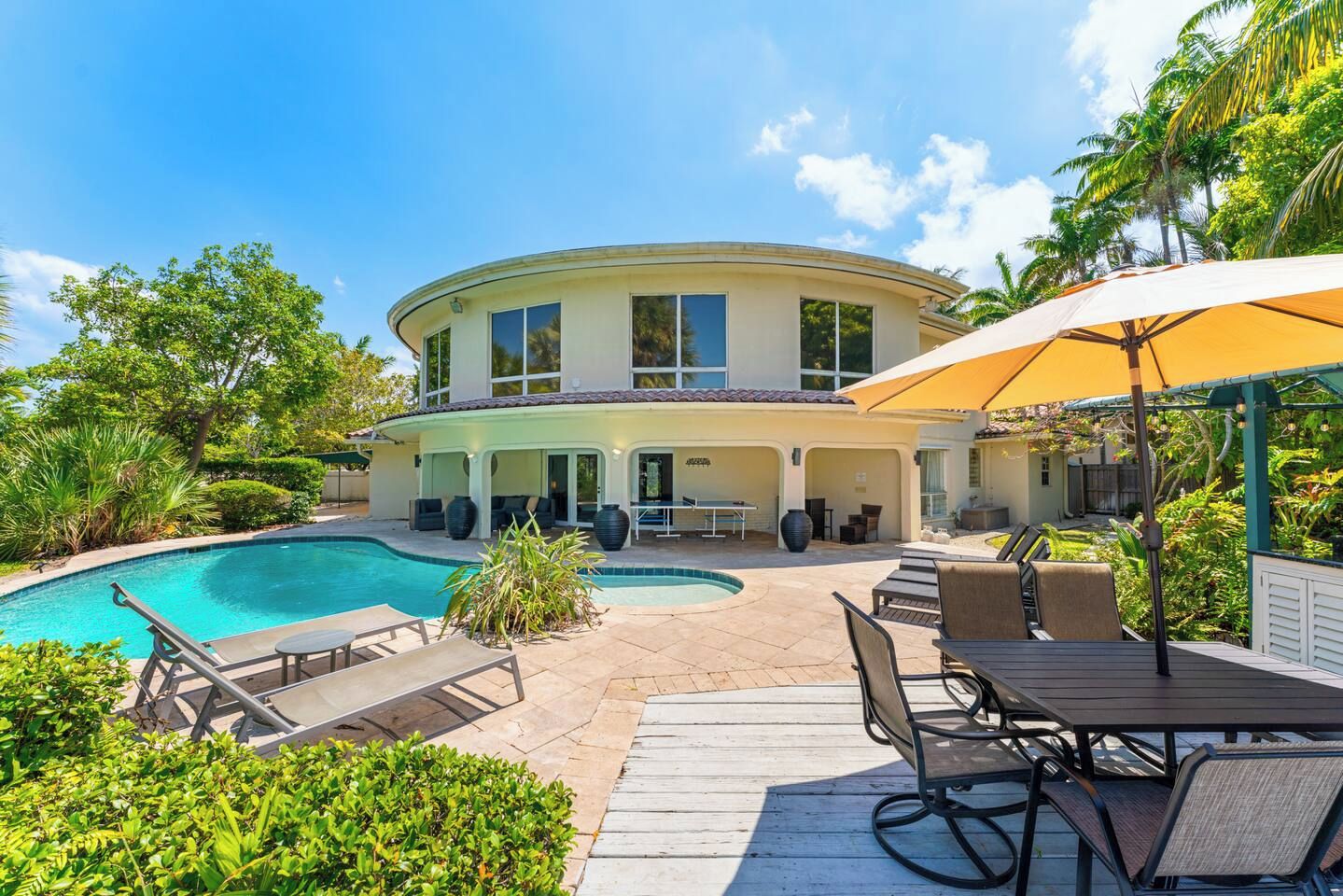 A two-story house with a swimming pool, outdoor seating, and a covered patio area.