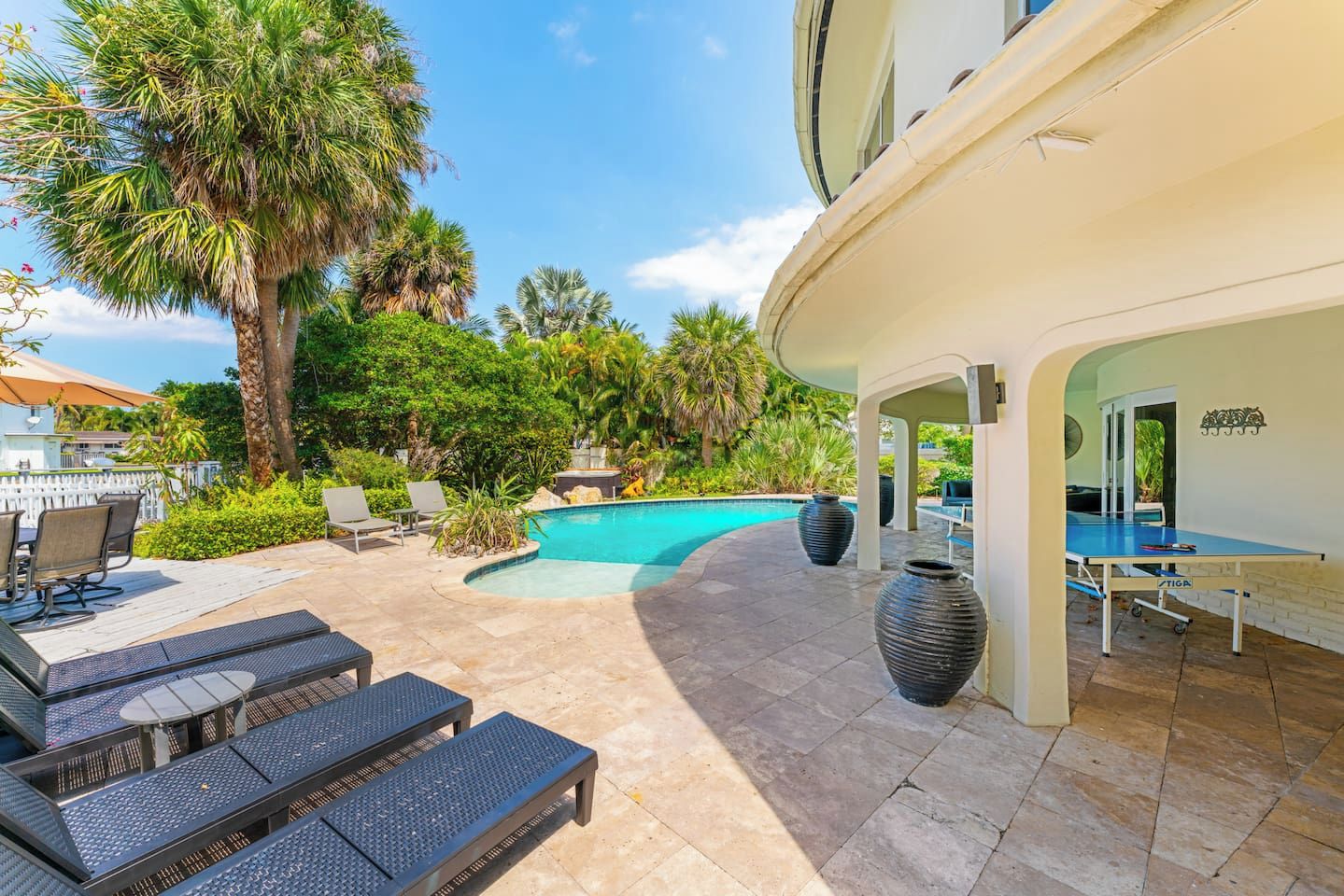 A pool area with lounge chairs, a table, and a ping pong table.