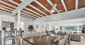 Un vaste espace dédié à la salle à manger, avec une table et des chaises en bois, un ventilateur de plafond et une vue sur le salon.