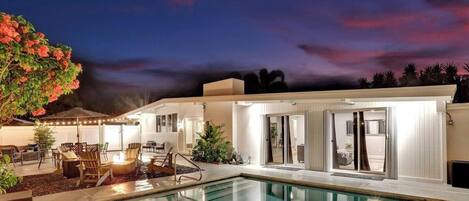 A modern outdoor pool area with a lounge, seating, and a view of the pool.