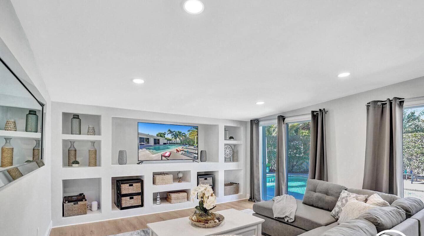 Una sala de estar moderna con una televisión de pantalla plana, un sofá gris y una mesa de centro con adornos decorativos.