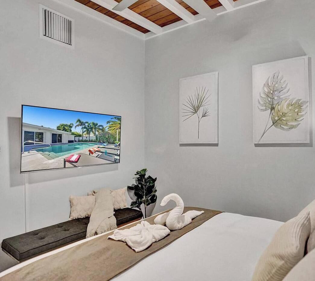 Un dormitorio con cama, televisión y obras de arte en la pared.