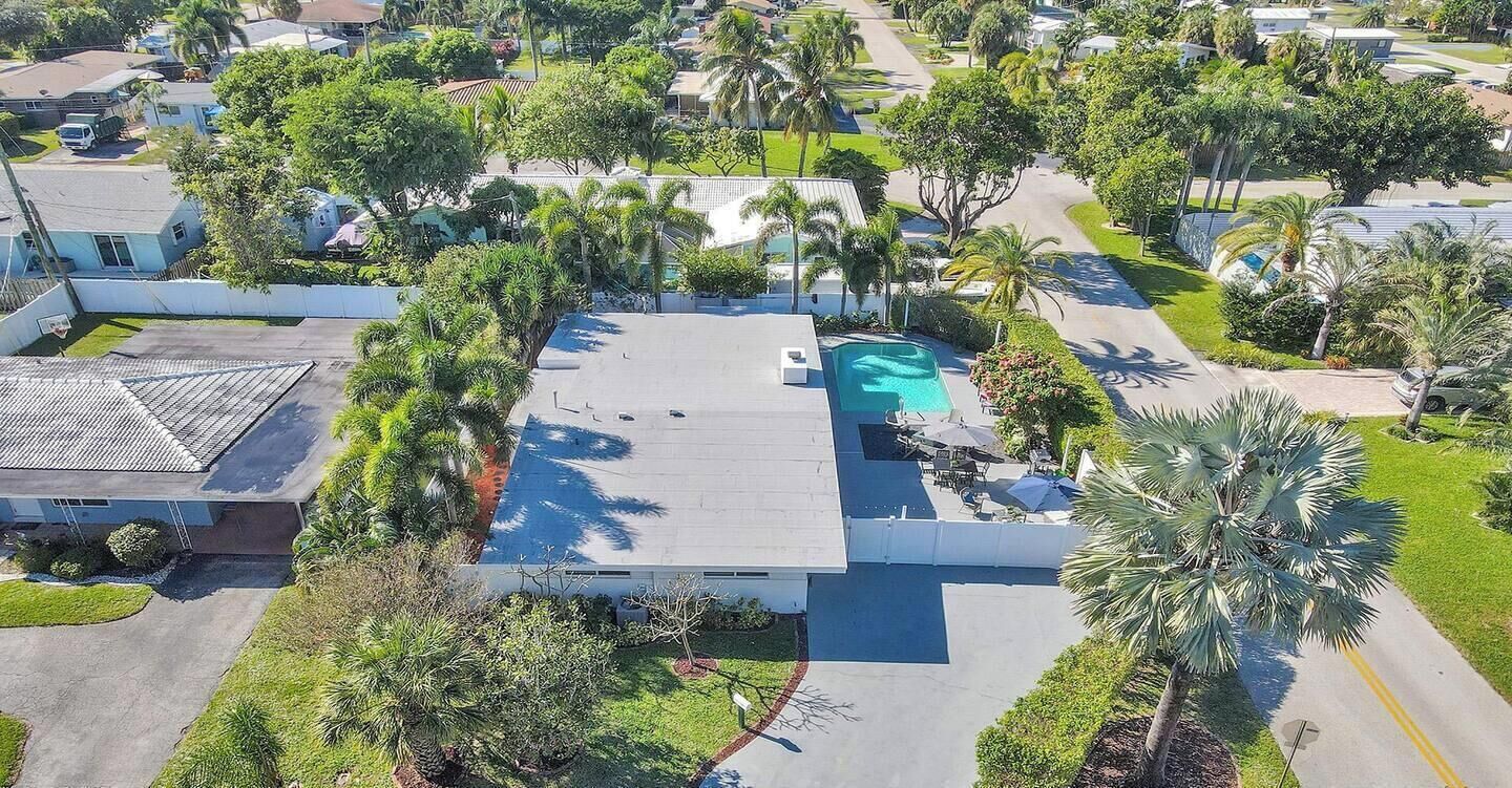 A residential area with a swimming pool, palm trees, and houses.