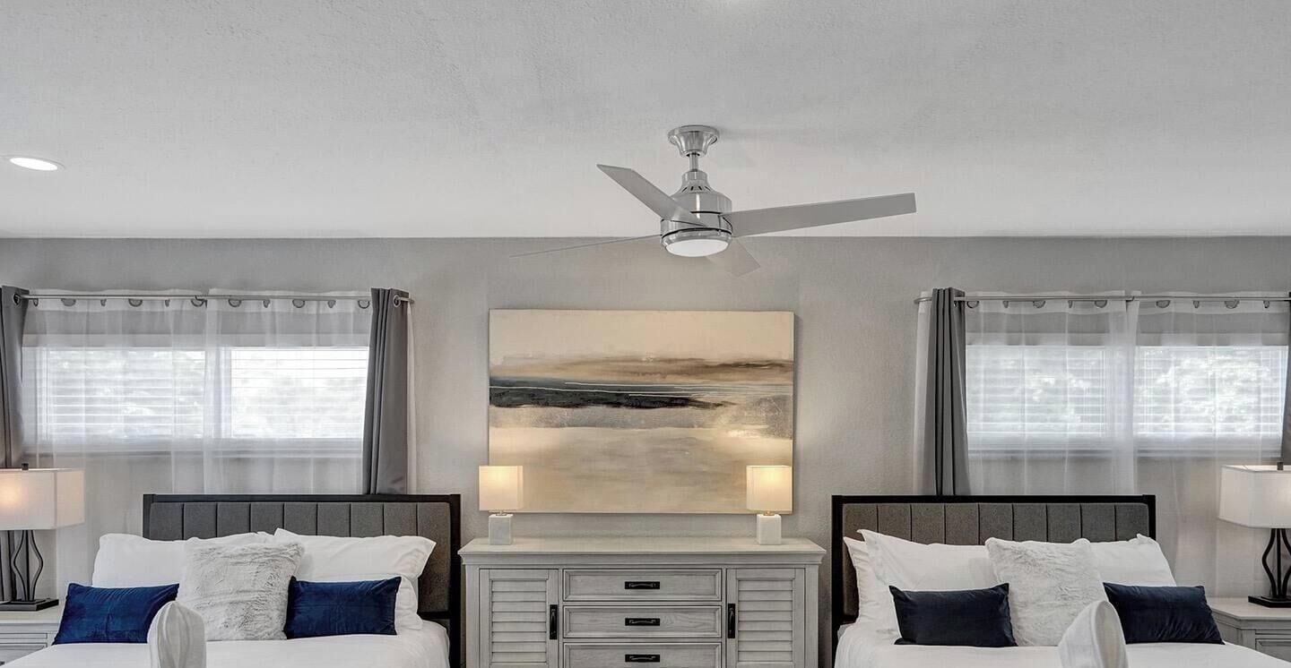 A hotel room with two beds, a ceiling fan, a large abstract painting, and a nightstand with lamps.