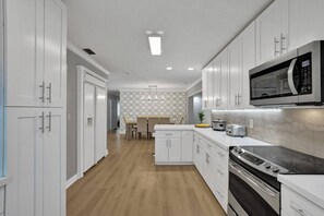 A modern kitchen with white cabinets, a microwave, a toaster, and a stove.