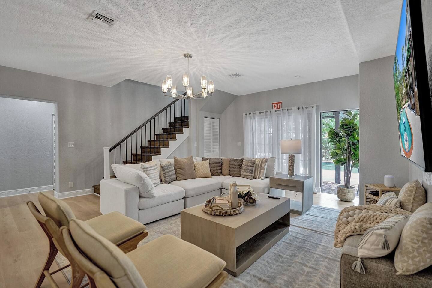 A spacious living room with a large sectional sofa, a coffee table, and a staircase leading to another level.