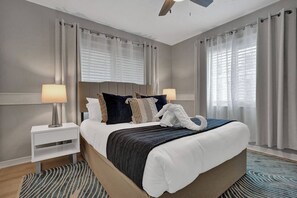 Ein Hotelzimmer mit einem Bett, Nachttischen, einem Deckenventilator und einem Fenster mit Vorhängen.