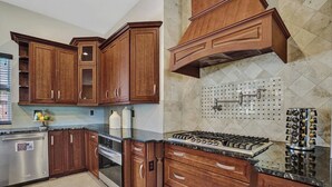 Eine Küche mit Holzschränken, einem Edelstahlkühlschrank, einem Einbauofen und einem Gasherd.