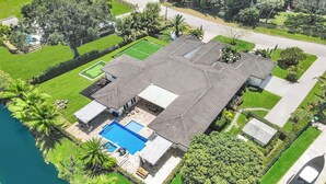 Ein Wohnhaus mit Schwimmbad, Tennisplatz und großem Rasen.