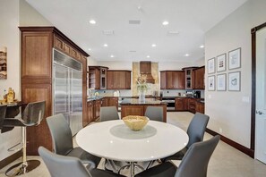 Una cocina moderna con una isla central, armarios de madera oscura y un comedor con una mesa redonda y sillas.
