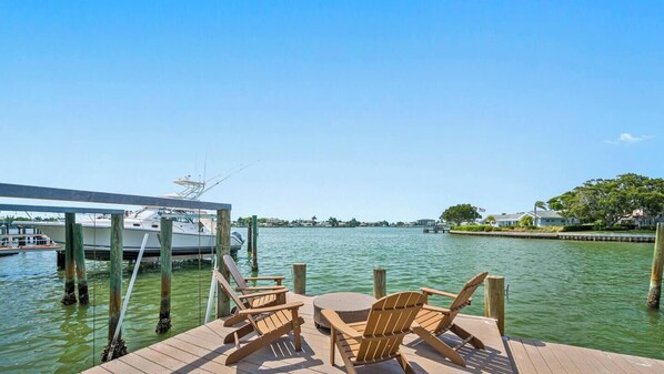 A wooden dock with chairs and a table, a boat docked to the left, and a clear view of the water and distant shoreline. - Waterfront - Private Pool - Game Room (Largo)
