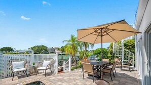 Eine Terrasss mit Pool, Esstisch, Stühlen und einem großen Sonnenschirm.
