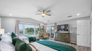 A hotel room with a large bed, a ceiling fan, a television, and a view of the outdoors. - Waterfront - Private Pool - Game Room (Largo)