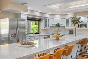 A modern kitchen with a central island, stainless steel appliances, and a view of greenery outside. - Pool - Soccer - Movie Room - Game Room - Sleeps 20 (Largo)