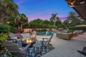 An outdoor pool area with lounge chairs, a fire pit, and a seating area with a view of the pool. - Pool - Soccer - Movie Room - Game Room - Sleeps 20 (Largo)