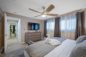 A hotel room with a bed, a dresser, a ceiling fan, a TV, and a view of the outside. - Pool - Soccer - Basketball - Game Room - Sleeps 20 (Largo)