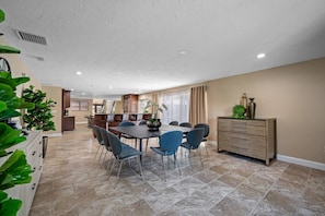 A spacious dining area with a large table and chairs, a kitchen in the background, and a staircase leading to an upper level. - Pool - Soccer - Basketball - Game Room - Sleeps 20 (Largo)