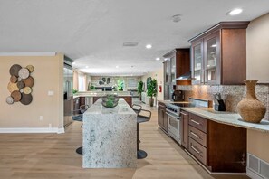 A modern kitchen with a central island, stainless steel appliances, and wooden cabinetry.