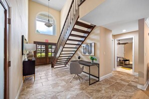 A spacious interior with a staircase, a desk, and a view of the outdoors.