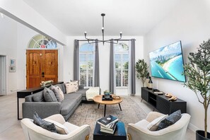 Una sala de estar moderna con un sofá gris, una mesa de centro y un televisor que muestra una vista panorámica.