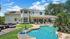 Une maison à deux étages avec une piscine, un patio couvert et une pelouse.