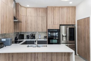 Una cocina moderna con armarios de madera, un refrigerador de acero inoxidable y un horno empotrado.