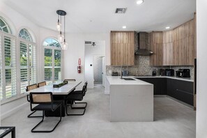 Una cocina moderna con una isla central, armarios de madera y un comedor con mesa y sillas.