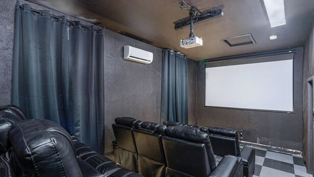 Une salle équipée d’un écran de projection, d’un système de climatisation et de sièges en cuir.