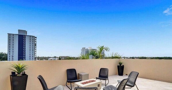 A rooftop terrace with outdoor seating, a fire pit, and a view of surrounding buildings. - Luxury villa w/pool, rooftop bar & fire pit (Pompano Beach)