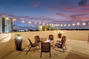 A rooftop terrace with outdoor seating, a fire pit, and string lights. - Luxury villa w/pool, rooftop bar & fire pit (Pompano Beach)