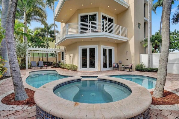 A two-story building with a swimming pool, outdoor seating, and palm trees. - Luxury villa w/pool, rooftop bar & fire pit (Pompano Beach)