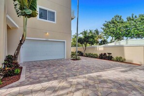 A residential property with a garage, paved driveway, and landscaped garden. - Luxury villa w/pool, rooftop bar & fire pit (Pompano Beach)