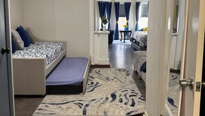 Una habitación de hotel compacta con una cama, un pequeño espacio de descanso, un espejo y una puerta.