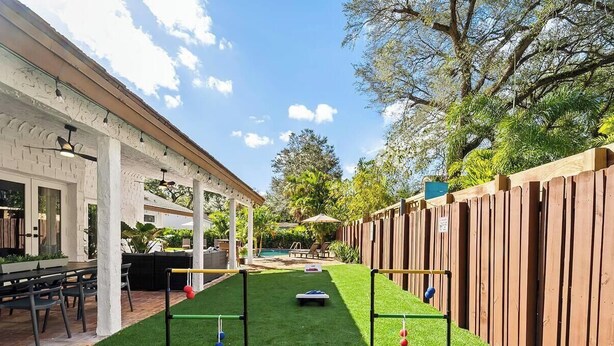 A patio area with a pool, a wooden fence, and a covered seating area. - Villa w/Pool, Firepit & BBQ (Dania Beach)