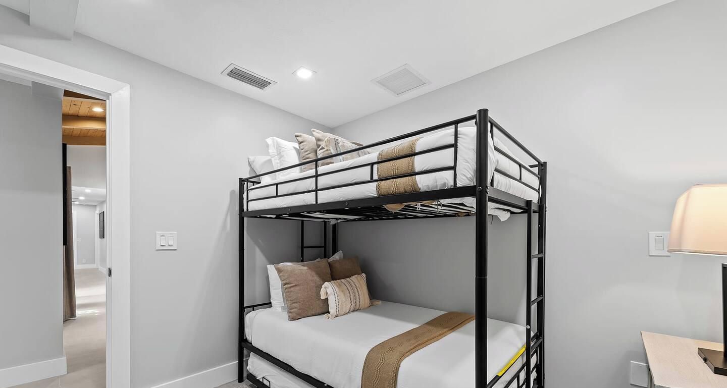 Une chambre avec un lit superposé, un bureau et une lampe.