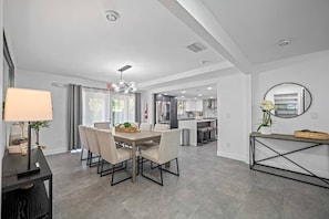 A modern kitchen with stainless steel appliances, a dining area with a table and chairs, and a living space with a sofa and a lamp. - Pool - Basketball -Soccer - Game Room - Playground (Largo)