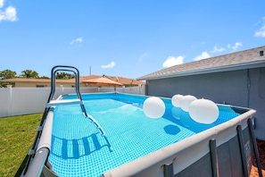 An outdoor swimming pool with a ladder, surrounded by a white fence, and a house in the background. - Spacious 4BR w/ pool, BBQ grill & theatre room (Bradenton)